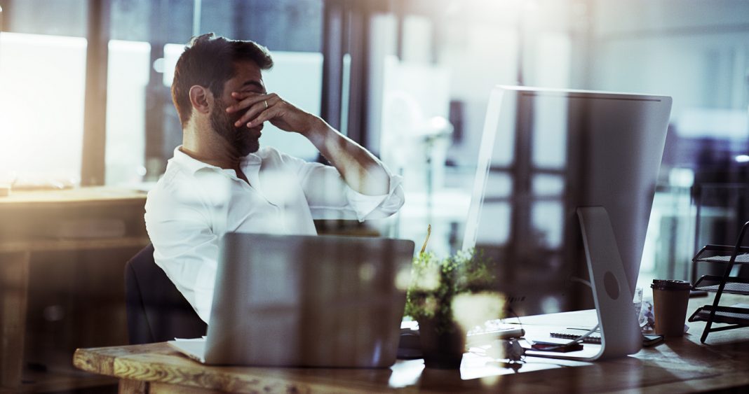 Cropped shot of a young businessman looking stressed while working late in the office